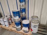 Plusieurs seaux de peinture sont posés sur une palette devant un mur.