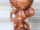 une statue en bois représentant un homme tenant un bol sur la tête