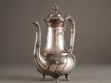 silver plated coffee pot on stand against a gray background