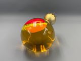 a small glass object with a red and yellow design on it