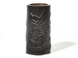 a black vase with a design on it on a white surface