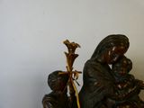 une statue représentant une femme tenant un enfant dans ses bras et un homme agenouillé à ses côtés