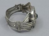silver bracelet with a green stone in the middle of it