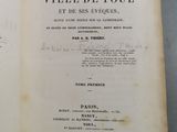 deux pages d'un livre, sur lesquelles figurent des inscriptions, posées sur une table