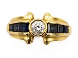 a close up of a gold ring with a diamond and sapphire stones