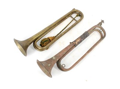 deux vieux trombones en laiton posés l'un à côté de l'autre sur une surface blanche
