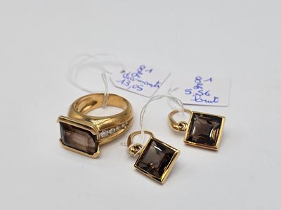 deux bagues et une paire de boucles d'oreilles sont posées sur une surface blanche