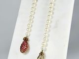 two pearl necklaces with a gold clasp and a red and white bead