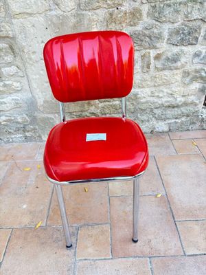 une chaise rouge posée devant un mur de pierre