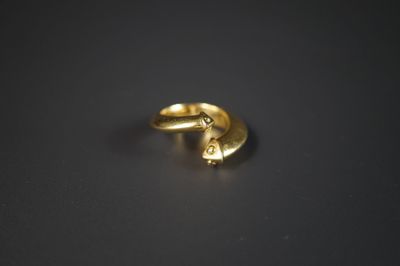 un gros plan sur une paire de boucles d'oreilles en or posées sur une surface noire