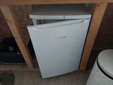 a small white refrigerator in the corner of a room