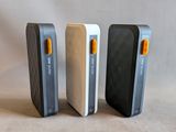 three cell phones are sitting side by side on a white surface