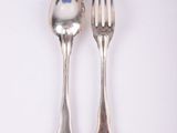 two silver spoons and a fork on a white surface