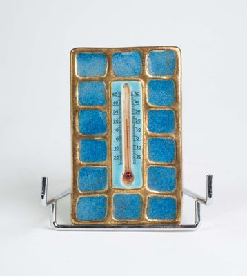 un thermomètre posé sur un support, sur une surface blanche