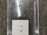 Une pomme et des AirPods se trouvent dans une boîte transparente posée sur un tapis