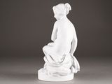 white statue of a woman sitting on a stool with her hands on her knees