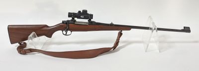 un fusil posé sur un support transparent, avec une arme dessus