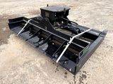 a close up of a black skid steer attachment on a dirt field