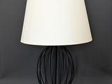 a black wire lamp with a white shade on top of it