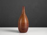 an orange vase sitting on top of a white table next to a black wall