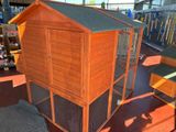 a large wooden chicken coop with a roof and a door