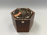 une boîte ancienne en bois contenant une horloge, posée sur une surface blanche