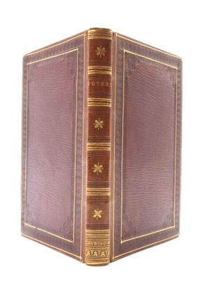 un vieux livre à la couverture brune et à la bordure dorée
