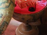 a red glass bottle sitting on top of a table next to a bowl