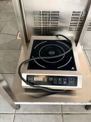 une petite cuisinière surmontée d'un brûleur noir