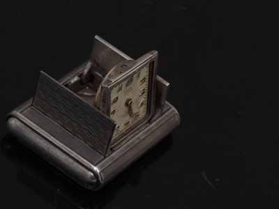 une horloge argentée posée sur une surface noire