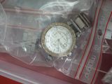 une montre dans un sac en plastique posée sur une surface rouge