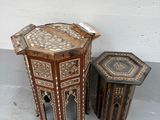 deux tables et un tabouret posés à même le sol devant un mur