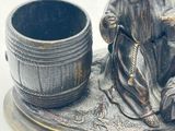 a statue of a man sitting next to a barrel