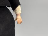 a close up of a doll wearing a black dress and a black jacket