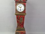 une horloge rouge et dorée posée sur une surface blanche