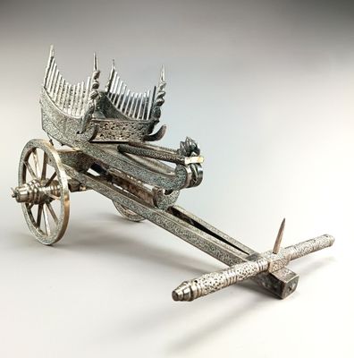 une maquette en métal argenté représentant une charrette sur laquelle est posé un oiseau