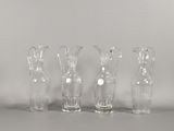 quatre vases en verre transparent posés les uns à côté des autres sur une table