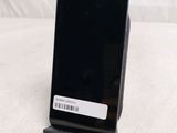 a black cell phone sitting on a stand on a bed