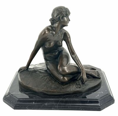 bronze statue of a woman sitting on a rock on a marble base