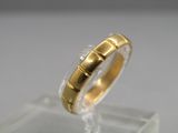 un gros plan d'une bague en or posée sur une surface transparente