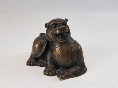 figurine en bronze représentant un singe assis sur une surface blanche