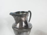 a silver pitcher sitting on a table next to a spoon