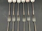 six spoons and a fork are lined up on a table