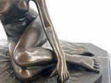a bronze statue of a woman sitting on a marble base