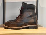 des bottes en cuir marron avec des lacets rouges, posées sur une étagère dans un magasin