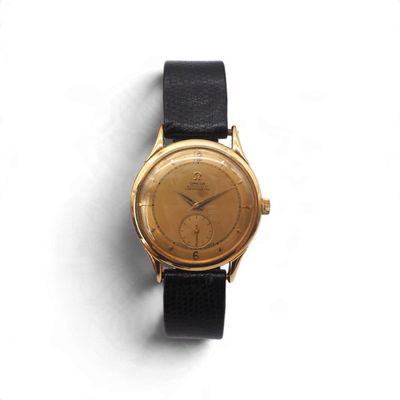 une montre en or avec un bracelet noir posée sur une surface blanche