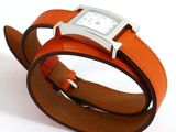 an orange leather bracelet with a silver square watch on it