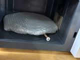a dog bed inside of a microwave on the floor