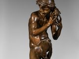 bronze statue of a boy holding a bird on a pedestal