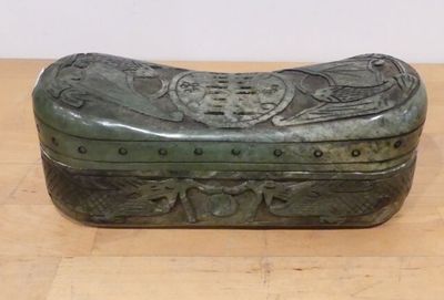 a green box sitting on a wooden table with a white wall behind it
